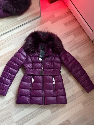 Lila vårjacka - Strl M ( liten L ). Jacka från märket Faina i snygg lila färg perfekt till våren. Nypris ca 2300kr Kragen är gjord i fuskpäls! 