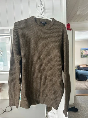Brun stickad tröja från SMOG - Säljer en brun stickad tröja från SMOG i regular fit. Tröjan har rund halsringning, långa ärmar och ett grovt ribbstickat mönster. Perfekt för dig som gillar en enkel och stilren look till hösten eller vintern.