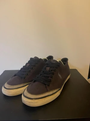 Ralfp lauren skor - Snygga låga sneakers i svart canvas med blåa snören och vit sula. Klassisk design med rund tå och diskret logga på sidan. Perfekta för en avslappnad streetstil och passar till det mesta i garderoben.