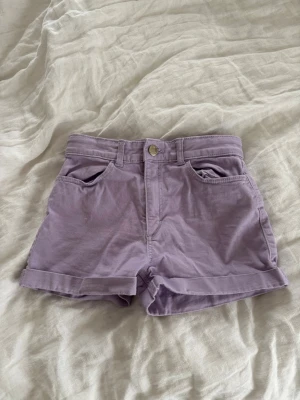 Ljuslila high waist shorts - Säljer ett par ljuslila högmidjade shorts med uppvikta benslut. Shortsen har bälteshällor och stängs med knapp och dragkedja. Perfekta för varma dagar och ger en fräsch look💜💜