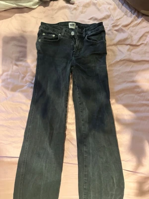 Svarta bootcut jeans från 157 - Säljer ett par svarta bootcut jeans från 157 med klassisk femficksdesign och silverfärgade knappar. Jeansen har en lätt utsvängd passform och är tillverkade i denim med en snygg tvätt. Perfekta för dig som gillar en avslappnad men trendig stil.