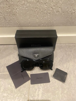 Prada solglasögon  - Svarta par solglasögon som är helt nya och som kommer med box och allt som finns med i bilderna.För mer frågor tveka ej!