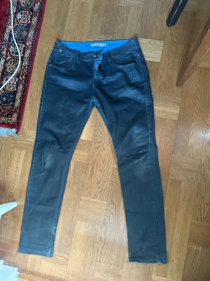 Svarta jeans från STORM - Snygga svarta jeans från STORM med klassisk femficksmodell och raka ben. Jeansen har en blå insida i midjan och detaljerade sömmar. Passar perfekt till en avslappnad och trendig stil.