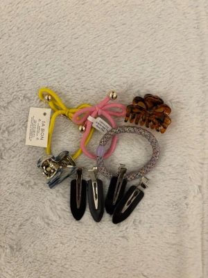 Ia bon, knekki och mer mix av hår saker - Säljer ett set med håraccessoarer: två hårsnoddar i gult och rosa med metallbollar, två hårklämmor i blått och brunt, en glittrig hårsnodd samt fyra svarta hårspännen. Perfekt för att variera din frisyr och addera färg till din look. Helt nytt mesta är oanvänd, man får alla 9 grejer