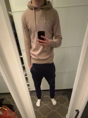 Beige merinoullhoodie - Snygg beige hoodie med huva och dragsko. Mjuk och skön känsla, perfekt för en avslappnad stil. Långa ärmar och ribbade muddar. Passar dig som gillar en enkel och stilren look. 100% merinoull från roge clothing. Modellen är 180 cm. Bara att skriva vid funderingar. Pris går att diskutera vid snabb affär!