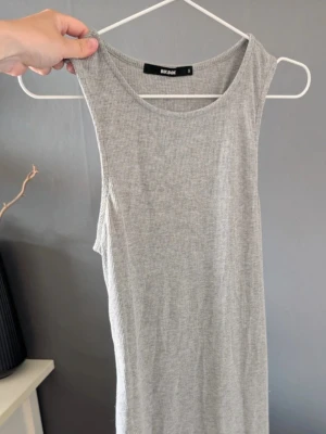 Grå ribbad ärmlös klänning Bik Bok - Säljer en ljusgrå ribbad klänning från Bik Bok. Klänningen är ärmlös och har en enkel, rak passform med rund halsringning. Perfekt till sommaren och lätt att styla med olika accessoarer.