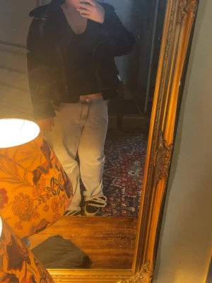 Svart mockateddy jacka från Zara - Snygg svart mocka Teddy jacka från Zara med bred krage, bälte i midjan och detaljer i fuskpäls. Jackan har dragkedja i sned modell, två framfickor med dragkedja och spännen vid kragen. Perfekt för dig som vill ha en edgy och trendig look. Lite smutsig på vänster arm fint skick ändå inte använd så mkt. Köpt på Vinted, storlek XL men skulle säga L för den e lite kort i armarna 💕 köp sker via köp nu‼️ 