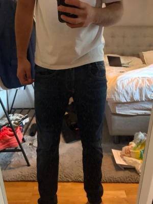 Jeans replay - Säljer ett par mörkblå slim fit jeans med klassisk femficksdesign och normal midja. Jeansen har en stilren look och passar perfekt till en avslappnad outfit. Materialet är troligtvis bomull med lite stretch för extra komfort.