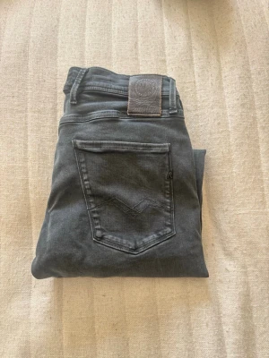 Replay grå jeans med raka ben - Snygga grå jeans från Replay med raka ben och klassisk femficksmodell. Jeansen har Replay-logga på bakfickan och patch i läderimitation vid linningen. Tillverkade i mjukt denimtyg som ger en skön passform och stilren look.
