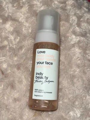 Indy Beauty rengöringsmousse - 100% vegansk rengöringsmousse från Indy Beauty med pumpflaska. Produkten är doftsatt och har en vit och beige design med text på framsidan. Perfekt för ansiktsrengöring och daglig hudvårdsrutin. Ny och förseglad
