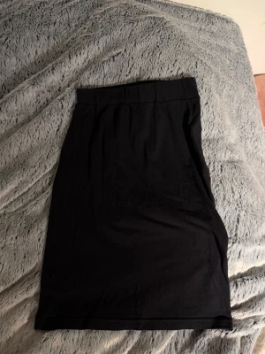 Svart enkel långkjol - Säljer en svart långkjol med rak passform och bred midjeresår. Kjolen är stilren och lätt att matcha till olika outfits. Perfekt för dig som gillar minimalistisk stil.