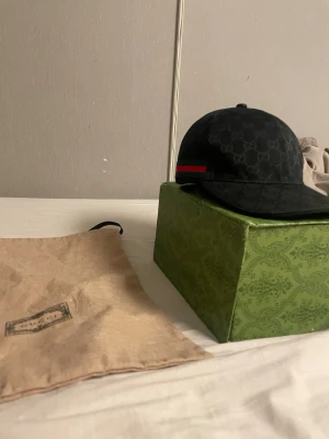 Svart Gucci keps med GG-mönster - Säljer gg keps storlek L. Får med Gucci lådan. Lådan är lite sönder på små ställen kepsen är helt ny använd 1-5 gånger 