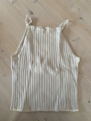 Ribbad vit linnetopp från H&M - Säljer en ribbad vit linnetopp från H&M i storlek 158/164. Toppen har smala axelband. Enkel och stilren design som passar till det mesta. Köparen står för frakt.