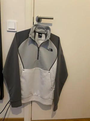 Grå och vit hoodie från The North Face - Säljer billigt för att den inte passar mig. Använd 1 gång! Sitter lite större