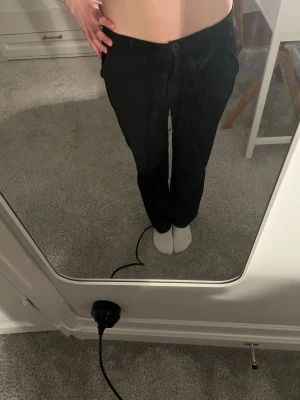 Svarta kostymbyxor med rak passform - Snygga svarta kostymbyxor med rak passform och klassisk midja. Byxorna har knapp och dragkedja framtill samt bälteshällor och sidofickor. Perfekta för en clean och stilren look.