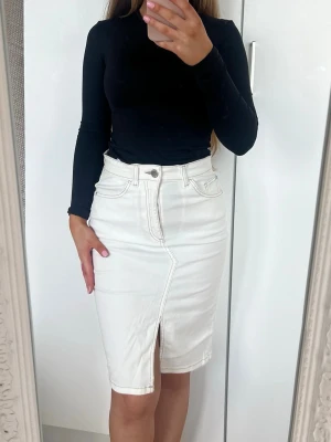 Kjol - Snygg vit jeanskjol i klassisk modell med fickor och en cool slits framtill. Kjolen har normal passform och stängs med knapp och dragkedja. Perfekt att matcha med en enkel topp för en clean look. Storlek XS. Stretchig. Fint skick 🩷