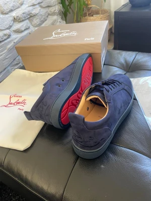 Mörkblå sneakers från Christian Louboutin - Snygga mörkblå sneakers från Christian Louboutin i mocka med klassisk röd sula och diskret logga på hälen. Helt nya aldrig använda eller testade 10/10 skick. Storlekar finns i 42/43/44/45. Allt tillbehör och OG medföljer. OBS tar slut snabbt!!! Pris kan diskuteras vid snabb affär!!