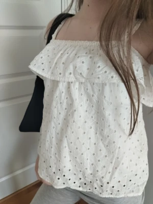 Jättefin sommartopp - Söt vit linnetopp med broderade hålmönster och volang upptill. Toppen är ärmlös med smala axelband och har en luftig, avslappnad passform. Perfekt för varma dagar och enkel att styla med jeans eller kjol. Stor i storlek