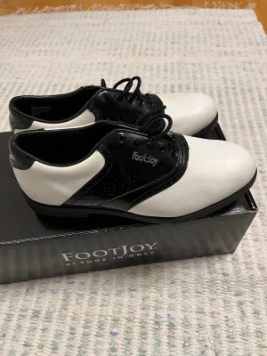 Footjoy Classic Golfskor - Säljer dessa Footjoy Classic golfskor, endast använda en golfrunda. Innermått 26 cm. Sulan på vänsterskon har lite-spikes Sulan på högerskon har soft-spikes Hör gärna av dig vid frågor:).       Kan samfrakta med mina andra annonser!