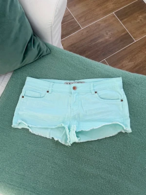 Turkosa lågmidjade jeansshorts  - Storlek 38 (M). Obs, för stora för mig (har klämma). Rakt över midjemått: 42cm. Gren: 20cm. Skickas inom 24h. Se liknande plagg i min profil!