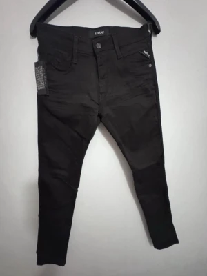 Svarta jeans Replay - Snygga svarta slim  jeans från Replay med klassisk femficksdesign och dragkedjegylf. Jeansen har en smal passform och är tillverkade i ett stretchigt material för extra komfort. Perfekta för en trendig och avslappnad look.