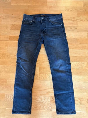 Svarta  jeans från Nudie Jeans - Säljer ett par svarta jeans från nudie. Jeansen har inga slitningar eller defekter och har  Nudie Jeans signaturbrodyr på bakfickan 