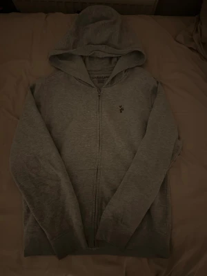 Grå hoodie från U.S. Polo Assn - Säljer en grå zip-hoodie från U.S. Polo jag har knappt andvänt den och tröjan är väldigt ny, 