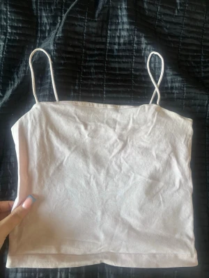 Babyrosa linnetopp - Säljer en babyrosa bandeau linnetopp från Gina tricot  med tunna axelband. Toppen är enkel och stilren, perfekt att matcha med jeans eller kjol. Materialet känns mjukt och lätt, vilket gör den skön att bära under varma dagar.