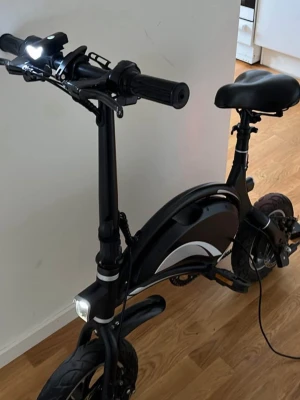 Svart elcykel med LED-lampor använd men inga problem - el cykel åker 25-30 har några dmå skador som kan fixas ingår laddare