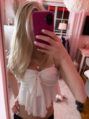 Vit sommar topp! - Superfin vit bandeau topp i satinliknande material med knyt framtill. Toppen är axelbandslös och har en flowy, omlottliknande nederdel som ger en romantisk känsla. Perfekt för sommaren och lätta outfits. Köpte secondhand och har ingen lapp, säkert något märke som inte finns kvar! Använd max 1 gång