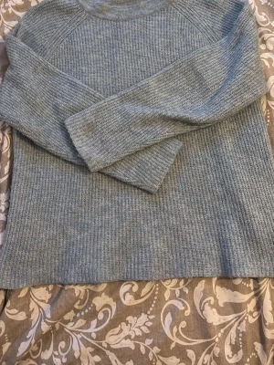 Ljusblå stickad tröja - Mysig ljusblå stickad tröja med rund hals och långa ärmar. Tröjan har en enkel, rak passform och är ribbstickad över hela plagget. Perfekt för lager på lager under kyliga dagar. Storlek L men sitter som S/M. 