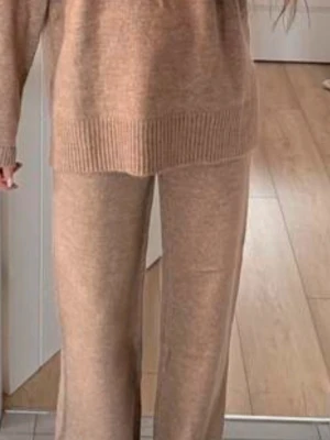 Beige stickat loungewear-set - Mysigt loungewear-set i beige stickat material med avslappnad passform. Setet består av en långärmad tröja med bred ribbad kant nedtill och matchande byxor med raka ben. Perfekt för chill dagar hemma. Materialet ser ut att vara mjukt och stretchigt.Andvänd en gång.Inga defekter