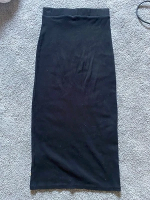 Svart långkjol från Zara - En stilren svart långkjol från Zara med rak passform och hög midja. Kjolen är enkel och klassisk, perfekt att matcha med olika toppar. Tillverkad i mjukt material som känns skönt mot huden.