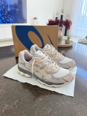 Asics GEL sneakers beige och grå - Snygga Asics GEL sneakers i beige och grå toner med mesh och mockadetaljer. Skorna har en chunky sula och klassisk Asics-logga på sidan. Perfekta för dig som gillar sportig och trendig stil.