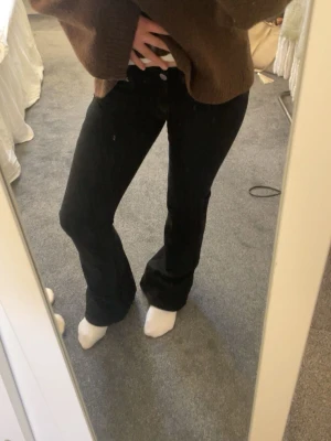 Svarta utsvängda jeans - Säljer ett par svarta utsvängda jeans med mid midja. Jeansen stängs med knapp och dragkedja. Perfekta för en avslappnad och stilren look.