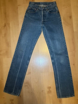 Klassiska raka blåa jeans från Levis 501or - Klassiska blåa Levis jeans med rak passform⭐️ De är i väldigt gott skick och visar inga tecken på slitage! Storlek: W27 L36 Midjemått rakt över: 30 cm Inre benlängd: 79 cm (Sitter som en xs) Tillverkade i ett mycket slitstarkt jeansmaterial med den ikoniska läderlappen bak i midjan, och den röda levis taggen på bakfickan🙏