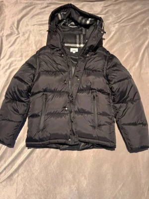 Svart pufferjacka från Burberry - Säljer nu en svin snygg Burberry jacka som även går att göra om till en väst och blir därmed flexibel till fler årstider! | Mycket bra skick och använd enstaka gång, inga defekter alls | Passar storlek M/L skulle jag säga | Pris 799 | Vid frågor är det bara att höra av sig! :)  