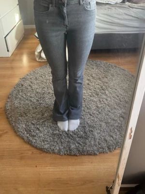 Grå bootcut jeans från ONLY - Säljer ett par grå bootcut jeans från ONLY med klassisk femficksmodell och normal midja. Jeansen har en snygg tvättad look och är tillverkade i mjukt denimtyg med lite stretch för extra komfort. Perfekta till sneakers eller boots!