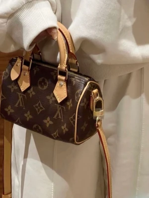 Louis Vuitton💖 - Säljer en brun handväska från Louis Vuitton med klassiskt monogrammönster. Väskan har beige läderhandtag och detaljer, samt guldfärgade metalldelar. 