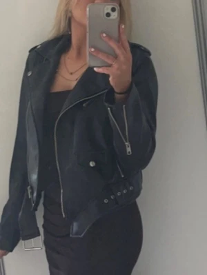 Svart skinnjacka med bälte - Snygg svart skinnjacka med bälte vid midjan. Jackan är i storlek XS/S. Den är använd fåtal gånger och har inga märken eller tecken på användning. Jackan är ifrån Zara och den går inte att köpa längre. 