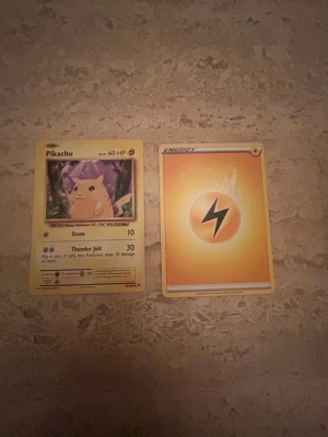 Två Pokémonkort: Pikachu & Energi - Säljer två från 2016 Pokémonkort: ett Pikachu-kort med 60 HP och attackerna Gnaw och Thunder Jolt, samt ett el-energikort. Båda korten har klassisk Pokémon-design med färgstarka motiv och blå baksida med Pokéboll. Perfekt till samlingen eller spelkvällar.