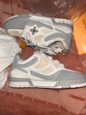 Louis Vuitton skate grey - Säljer ett par Louis Vuitton sneakers ljusgrått med meshpaneler och läderdetaljer. Skorna har LV-logga på plösen och sidan samt en chunky sula. Snygg design med blandning av material och klassiska LV-detaljer.