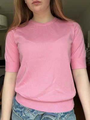 Rosa stickad topp med kort ärm - Söt rosa stickad topp med rund halsringning och korta ärmar. Jättefin att matcha med jeans! Perfekt färg nu till våren/sommaren!💗🌸 Tröajn är nyköpt och helt oanvänd! Pris kan diskuteras💗