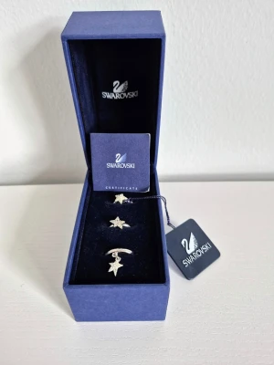 Swarovski Star Ring Set - 3 ringar - ✨ Elegant ring-set från Swarovski med tre separata vackra ringar i modellen Star Flicker.  Varje ring har en unik stjärndesign och kan bäras var för sig eller tillsammans (stackable).   - Storlek 52 (17 mm)  - Mycket fint skick - Set med 3 separata ringar - Tre olika stjärnor - Clear crystals satta med Pointiage-teknik💎  - Originalförpackning, originalbox, alla tags samt litet certificate-häfte ingår