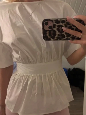 Vit blus med knyt i midjan - Supersöt vit topp med knytning i ryggen! Helt ny och aldrig använd, säljer då den inte kommer till användning💕