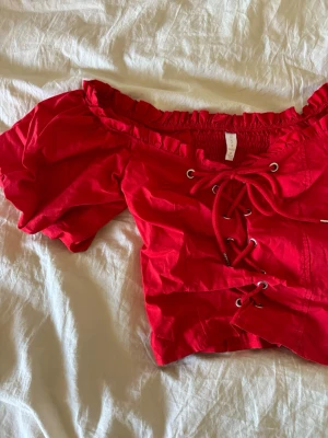 Unik Röd blus med snörning  - Söt röd blus med snörning, kort längd och puff armar och riktigt fin passform❣️