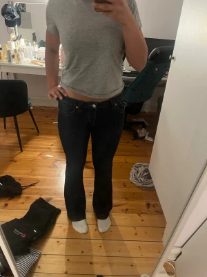 Mörkblå bootcut jeans - Säljer ett par mörkblå bootcut jeans med klassisk femficksdesign och kontrastsömmar. Jeansen har en något utsvängd passform nedtill och sitter snyggt över höfterna. Perfekta till en avslappnad look och passar till det mesta.