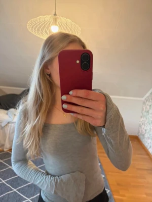Ljusgrå långärmad topp - En enkel och stilren ljusgrå långärmad topp med rundad urringning. Toppen är tight i modellen och har slits vid ärmarna