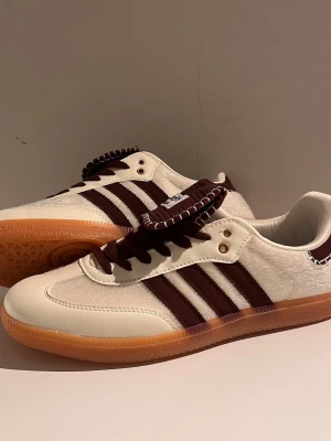 Beige och bruna sneakers med gummisula - Sneakers i beige och brunt med klassiska ränder på sidan, ovandel i mocka och textil samt detaljer i läder. Skorna har en låg siluett och en slitstark gummisula i ljusbrunt. Snygga kontrastsömmar baktill och bruna skosnören ger en unik look.