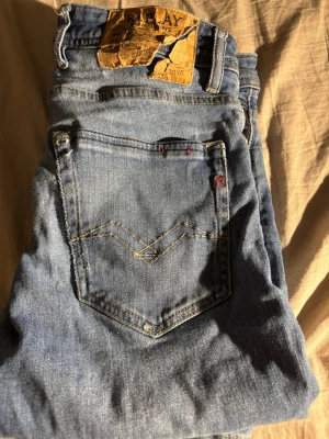 Ljusblå jeans från Replay, storlek 28 - Säljer ett par ljusblå jeans från Replay i storlek 28. Klassisk femficksmodell med snygga kontrastsömmar och Replay-logga på bakfickan. Jeansen har en avslappnad passform och är tillverkade i mjukt denimtyg. Lite slitna men funkar perfekt, säljer pga att de är för små!
